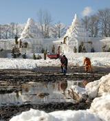 岩手雪まつりの会場で、地面が見えるほど雪不足の中、運んできた雪で雪像作りをする自衛隊員ら
